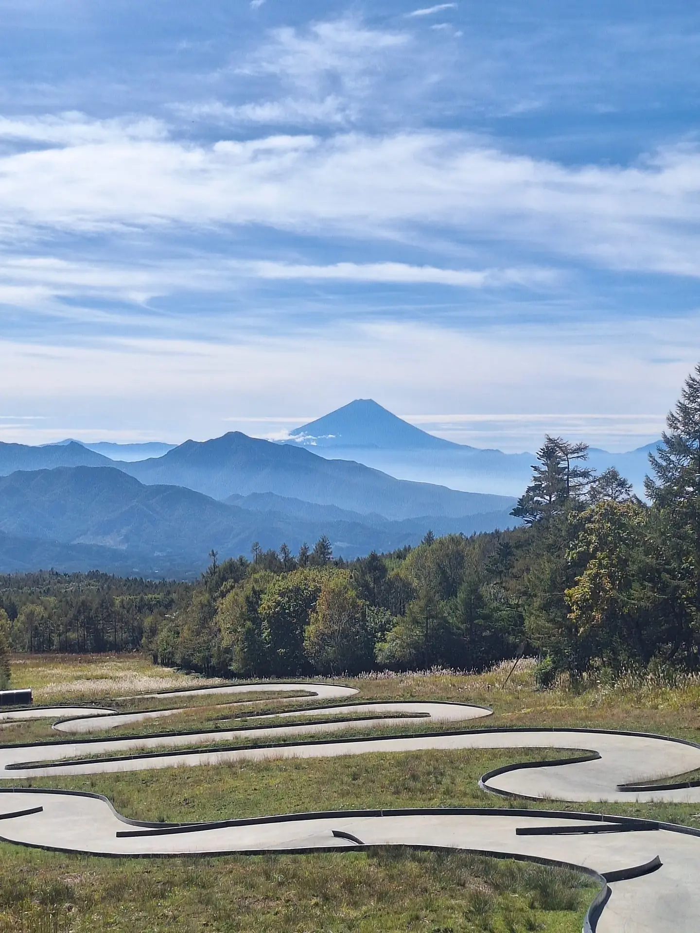 Outdoor go-kart pista em um gramado encosta com layered azuis montanhas e Mount Fuji centered em o antecedentes