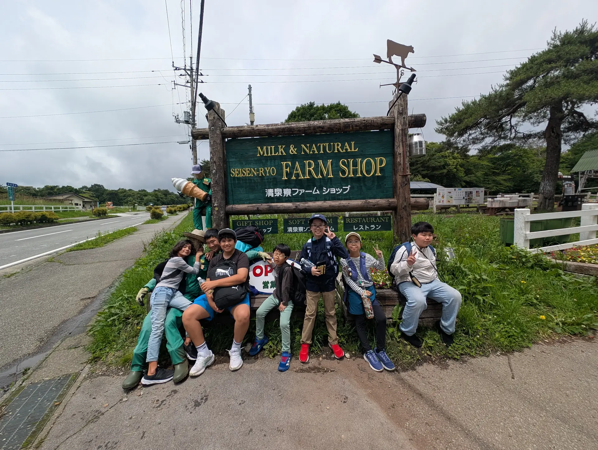 Campers posing beside o Seisen-ryo Farm Shop sign em Kiyosato