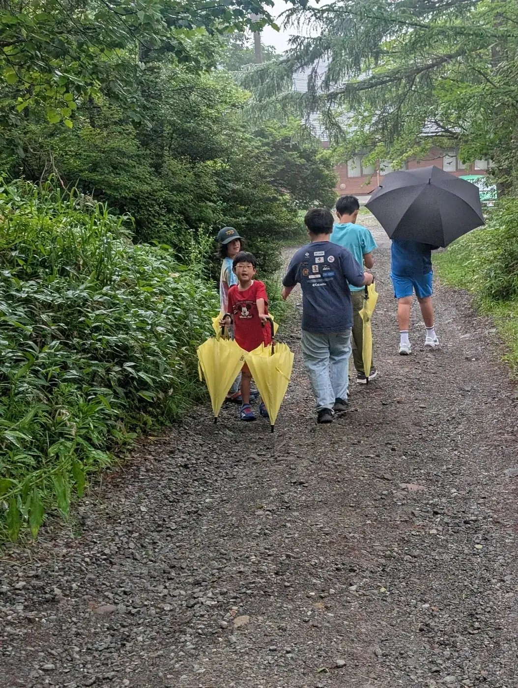 グループ旅行の日、清里駅の看板の下でポーズをとるキャンパーたち