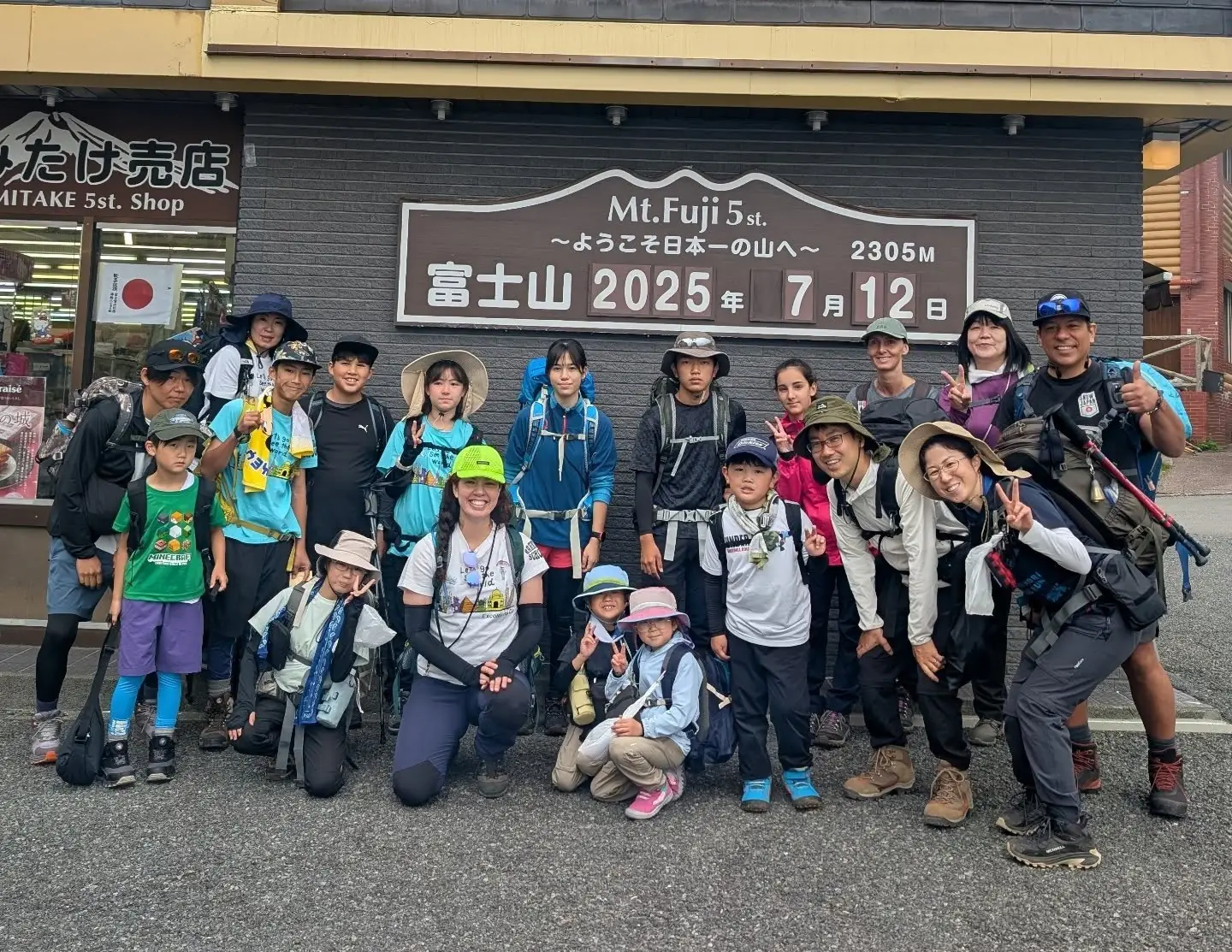 富士山五合目でポーズをとるキャンプ参加者と大人のリーダー